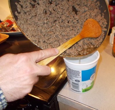 Photo clearly showing a skillet being drained of grease.